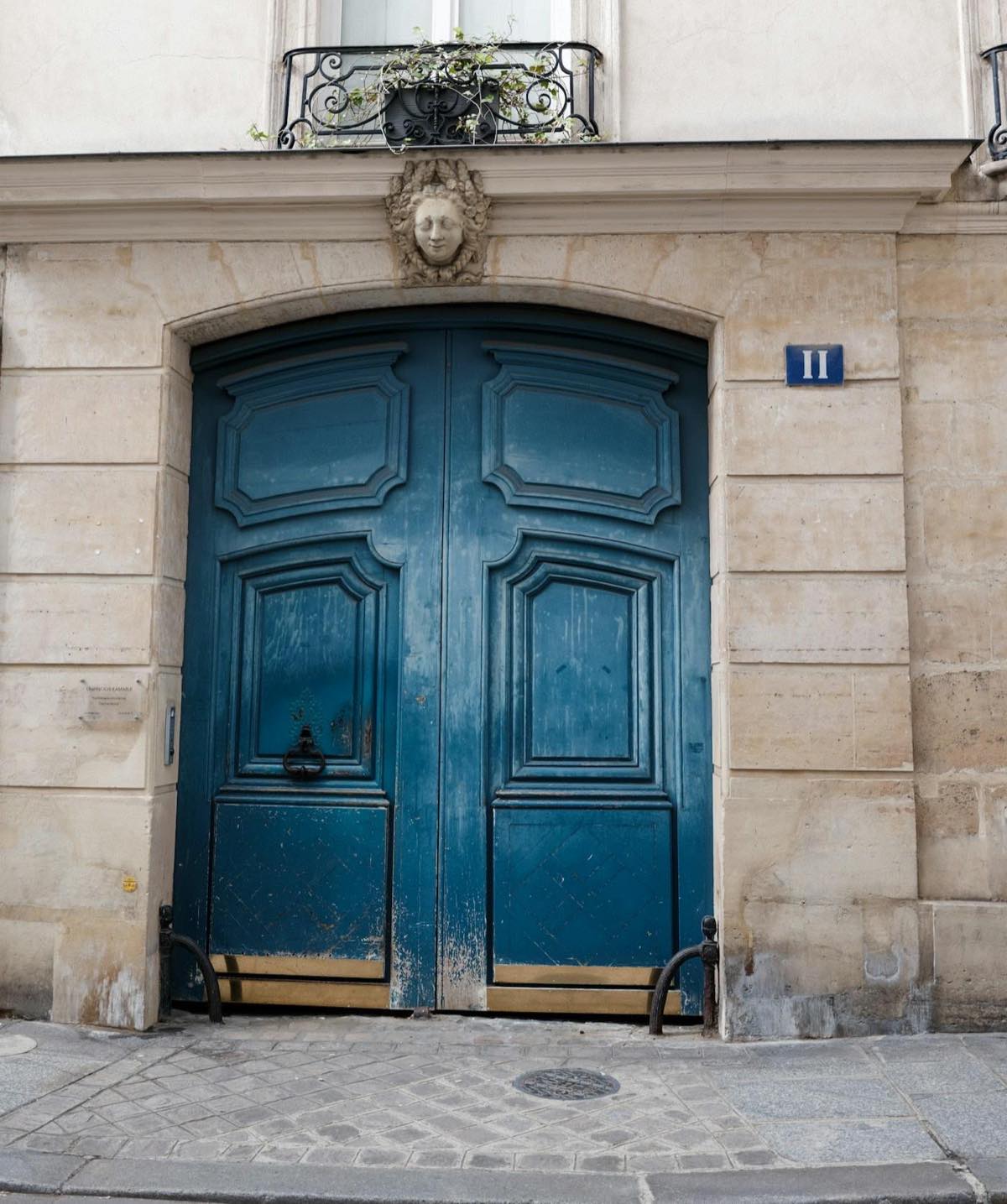 Porte coch&egrave;re ancienne &agrave; deux vantaux, mascaron de pierre sculpt&eacute; au-dessus de l&rsquo;arche.